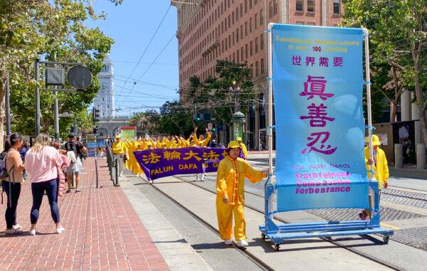 Pedestrians stop to watch a parade hosted by Falun Gong practitioners to celebrate over 400 million people quitting the Chinese Communist Party in San Francisco on Aug. 20, 2022. (Ilene Eng/NTD)