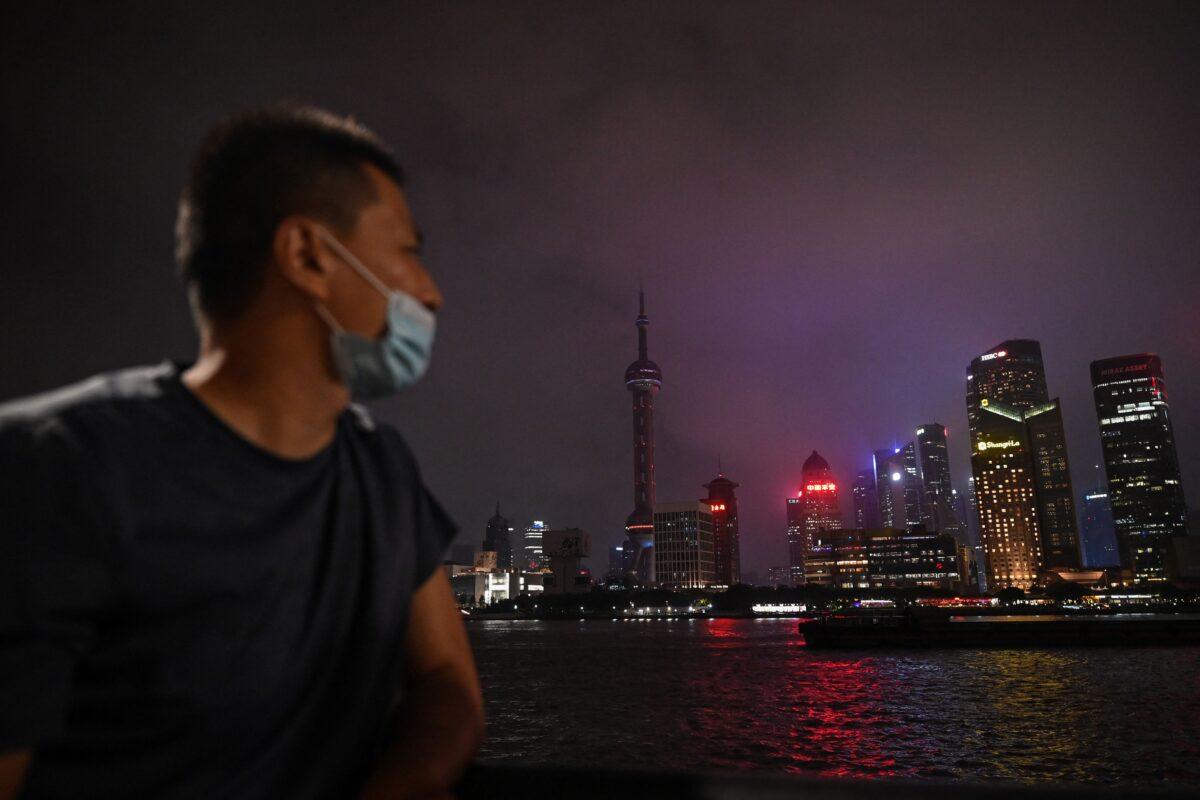 A man looks out from the Bund promenade along the Huangpu River as decorative lights are switched off as a measure to save energy in Shanghai on Aug. 23, 2022. (Hector Retamal/AFP via Getty Images)