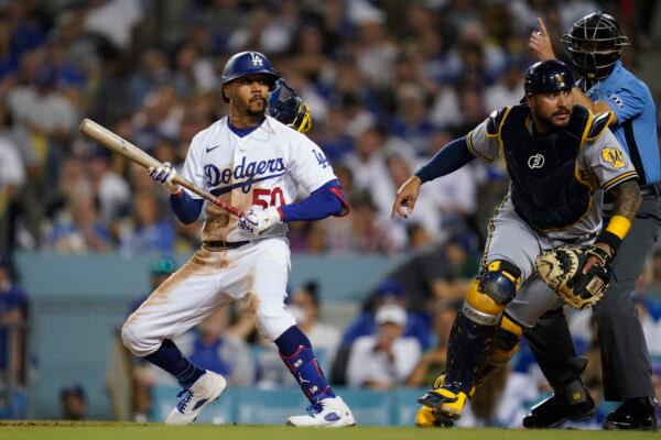 Los Angeles Dodgers' Mookie Betts (50) runs to first while Milwaukee Brewers catcher Omar Narvaez (10) chases a wild pitch during the fourth inning of a baseball game in Los Angeles, Aug. 23, 2022. (Ashley Landis/AP Photo)