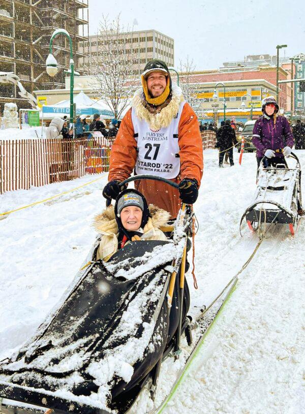 Sass behind an “IditaRider,” the winner of the annual bid for a short sled ride at the ceremonial start of the race. (Courtesy of Brent Sass)