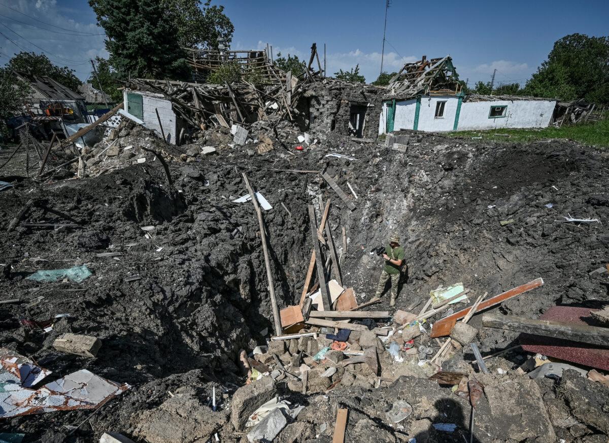 A Ukrainian service member stands inside a crater next to a residential house destroyed in Chaplyne, Dnipropetrovsk region, Ukraine, on Aug. 25, 2022. (Dmytro Smolienko/Reuters)