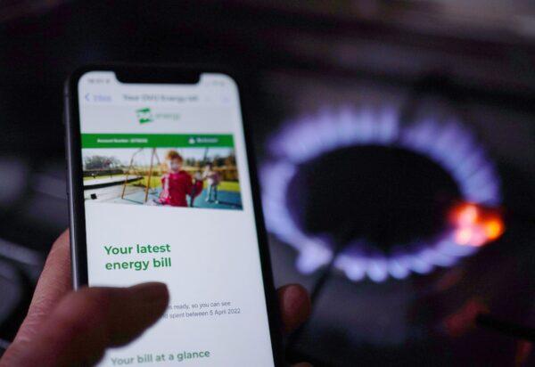 A household energy bill displayed on a mobile phone held next to a gas hob, in a file photo dated Aug. 25, 2022. (Yui Mok/PA Media)