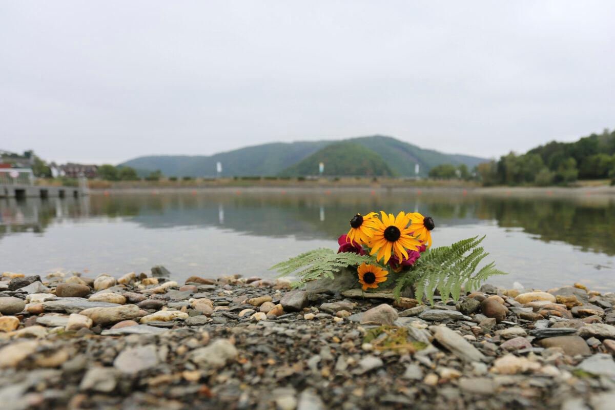 Flowers are left on the shores of Lake Eiserbach near Aachen, Germany, on Aug, 26, 2022. (Ralf Roeger/dpa via AP)