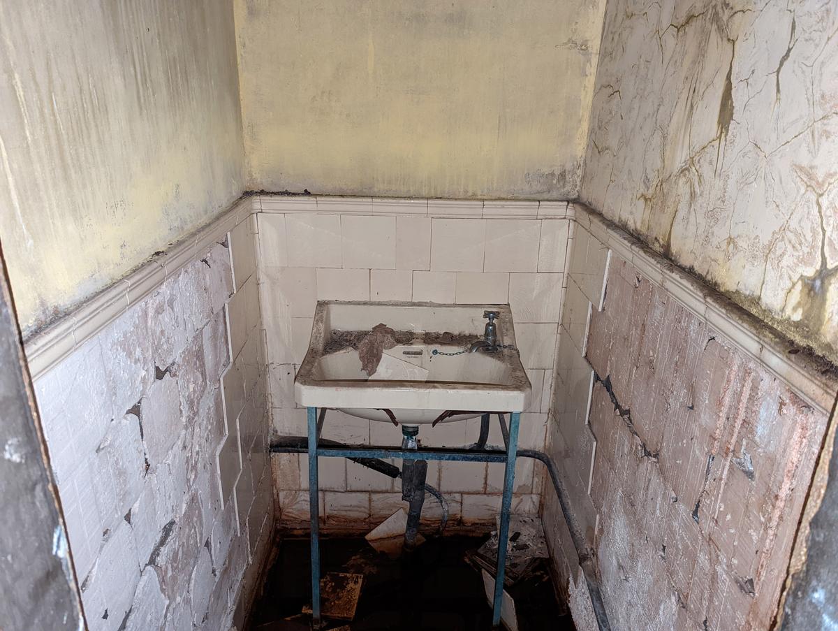 A sink fallen into disuse next to a broken tiled wall inside the facility. (Courtesy of Caters News)