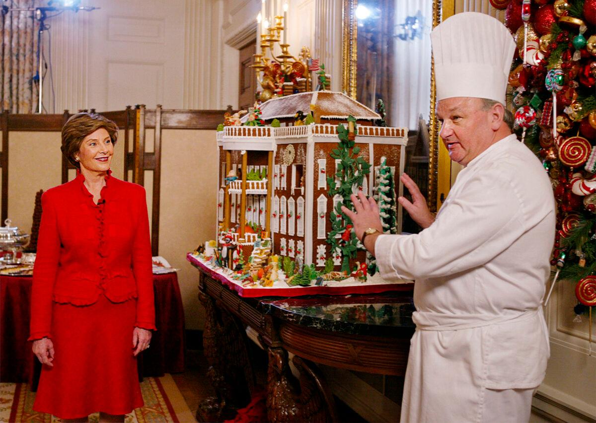First Lady Laura Bush listens to White House pastry chef Roland Mesnier (R) explain the components of the gingerbread White House in the State Dining Room, during a preview of the White House holiday decorations in Washington, on Dec. 4, 2003. (Manuel Balce Ceneta/AP Photo)