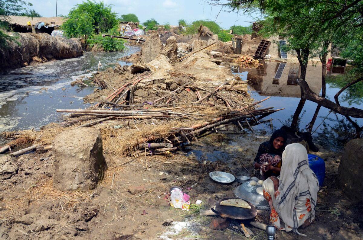 Pakistani women make bread near their damaged home surrounded by floodwaters in Jaffarabad, a district of Pakistan's southwestern Baluchistan province, on Aug. 28, 2022. (Zahid Hussain/AP Photo)