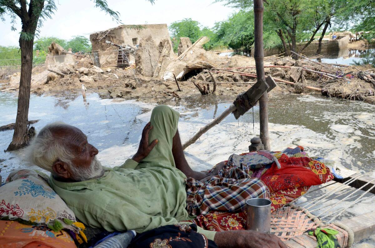 A man rests near his damaged home surrounded by floodwaters in Jaffarabad, a district of Pakistan's southwestern Baluchistan province, on Aug. 28, 2022. (Zahid Hussain/AP Photo)
