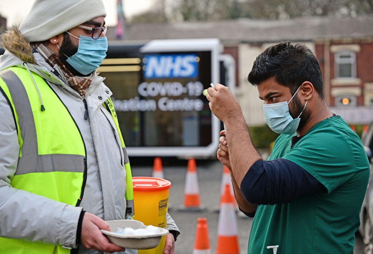 A health service worker draws up a dose of COVID-19 vaccine at a drive-through vaccination centre in Blackburn, England, on Jan. 17, 2022. (Paul Ellis/AFP via Getty Images)