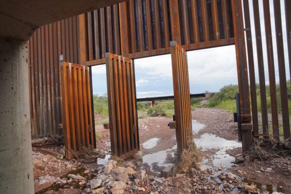 The doors to a section of border wall fence near Bisbee, Ariz., are left wide open on Aug. 25, ostensibly to prevent flooding, but allowing easy entry for illegal aliens coming up from Mexico. (Allan Stein/The Epoch Times)