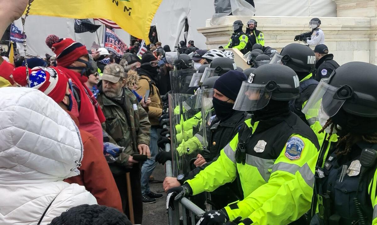 Mark Griffin of Canadensis, Pa., pulls his driver's license from his wallet to show to police at the barricades on the west side of the Capitol on Jan. 6, 2021. (Steve Baker/Screenshot via The Epoch Times)