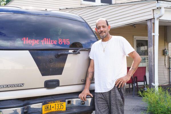 Domingo Ramos stands next to the vehicle that he uses to take him to areas of searches in front of his house in Middletown, N.Y., on Aug. 25, 2022. (Cara Ding/The Epoch Times)