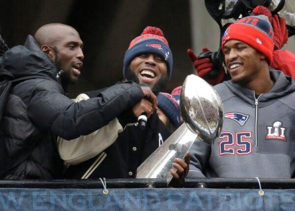 New England Patriots safety Devin McCourty, left, running back James White, center, and defensive back Eric Rowe (25) laugh with a Super Bowl trophy during a rally to celebrate Sunday's 34–28 win over the Atlanta Falcons in the NFL Super Bowl 51; in Boston, Feb. 7, 2017. (Elise Amendola/AP Photo)