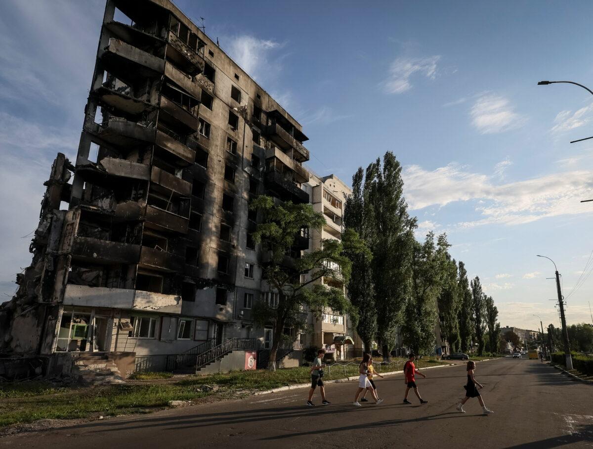 Teenagers cross a street in front of destroyed buildings amid Russia’s invasion of Ukraine, in the town of Borodianka, in Kyiv region, Ukraine, on Aug. 26, 2022. (Gleb Garanich/Reuters)