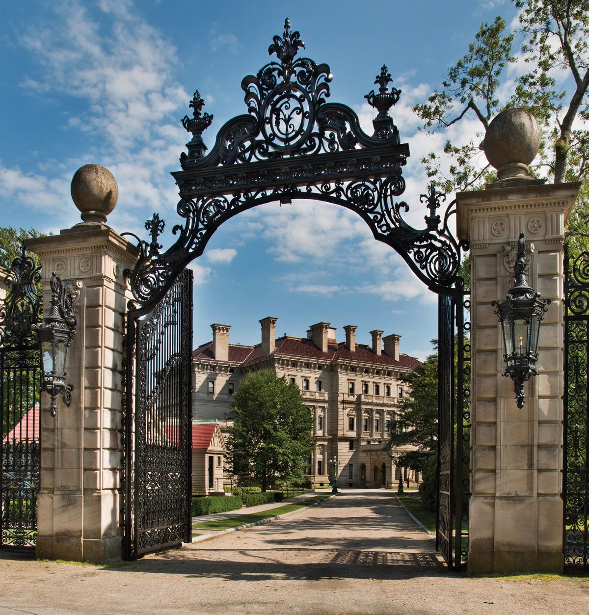 The entrance gates, manufactured by the William H. Jackson Company of New York, rise 30 feet above the driveway and feature a monogram of Cornelius Vanderbilt’s initials as well as acorns<br/>and oak leaves— symbolic of the Vanderbilt family. (Courtesy of The Preservation Society of Newport County)