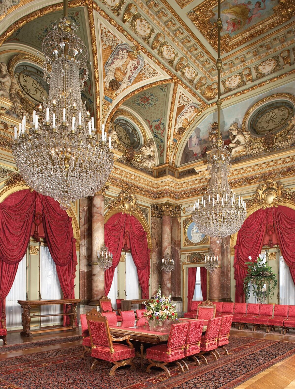 The Dining Room is the most lavish room inside The Breakers, featuring 12 rose alabaster Corinthian columns, a ceiling mural of the goddess Aurora bringing in the dawn on a four-horse chariot, and two Baccarat crystal chandeliers. (Courtesy of The Preservation Society of Newport County)