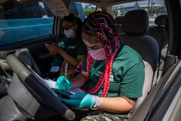 A Project Roomkey volunteer takes notes inside her car while waiting for a homeless person to arrive for her transfer to a hotel room in Venice Beach, Calif., on April 26, 2020. (Apu Gomes/AFP via Getty Images)