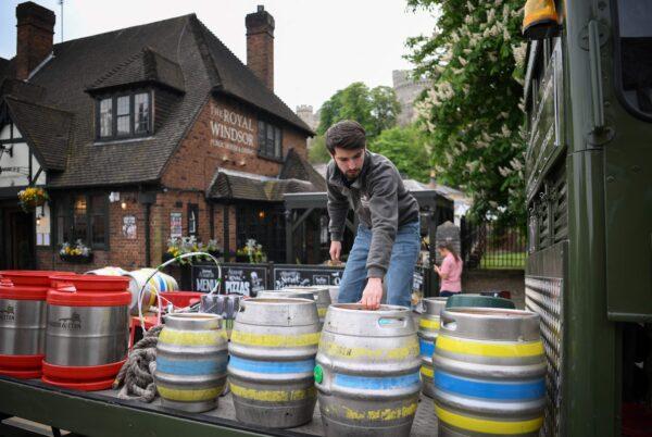 A workers picks up draft barrels of beer from a horse-drawn delivers to a pub where they serve different beers including the newly made pale ale beer for the Queens Jubilee Platinum celebration made by Windsor & Eton Brewery in Windsor, England, on April 28, 2022. (Daniel Leal/AFP via Getty Images)