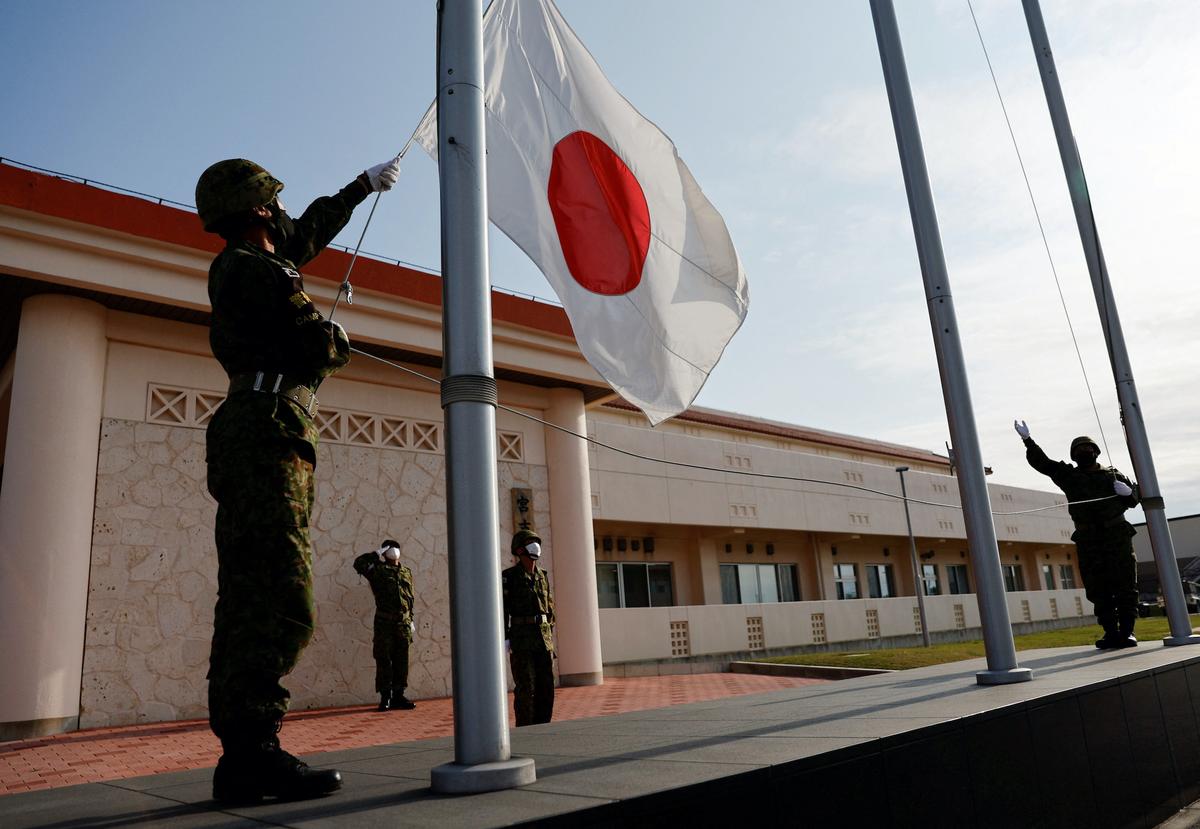 Members of the Japan Ground Self-Defense Force (JGSDF) bring down the Japanese national flag in the early evening at the JGSDF Miyako camp on Miyako Island, Okinawa prefecture, Japan, on April 20, 2022. (Issei Kato/Reuters)