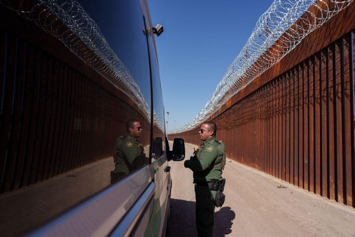 U.S. Border Patrol agent Carlos Rivera is reflected in the window of a vehicle as he speaks to another agent along the border wall in El Paso, Texas, on June 3, 2022.(Paul Ratje/AFP via Getty Images)