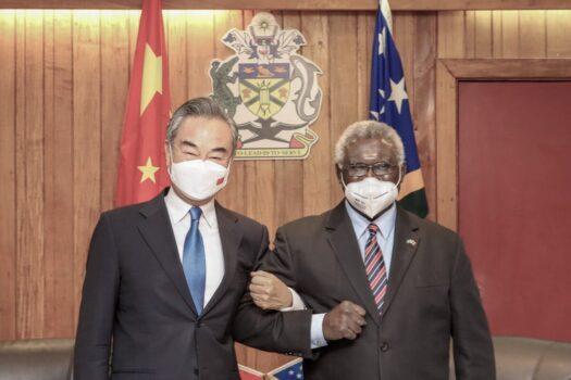 In this photo released by Xinhua News Agency, Solomon Islands Prime Minister Manasseh Sogavare, right, locks arms with visiting Chinese Foreign Minister Wang Yi in Honiara, Solomon Islands, on May 26, 2022. (Xinhua via AP)
