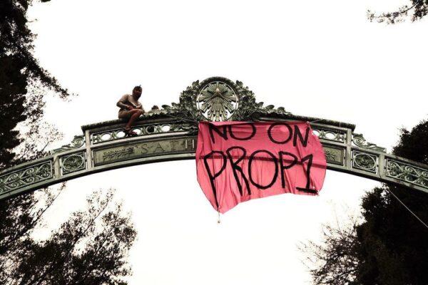 Maison Des Champs, known as “Pro-Life Spider-Man,” sits on top of Sather Gate at University of California Berkeley after hanging up a sign on Aug. 26, 2022. (Courtesy of Henry Barish)