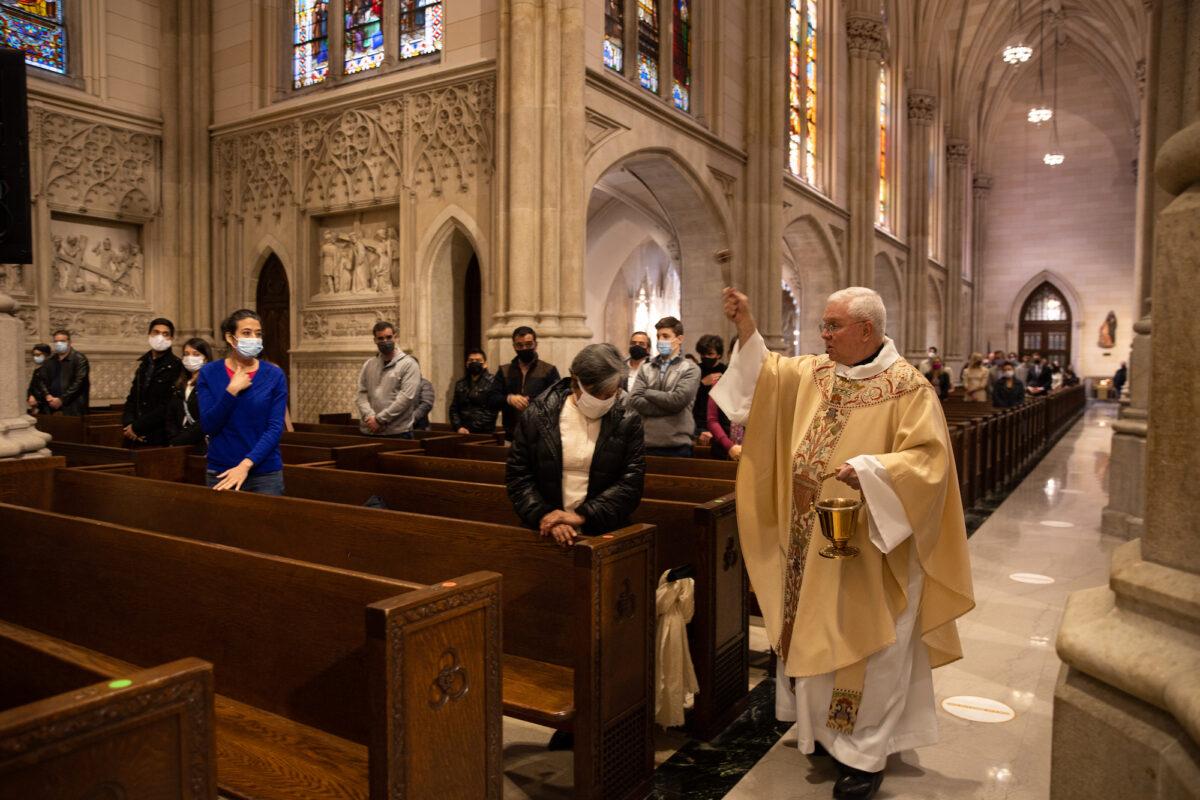 Father Ed Dougherty sprinkles holy water during a mass at Saint Patrick's Cathedral in New York on April 4, 2021. The annual Easter Parade and Bonnet Festival on Fifth Avenue is going virtual for the second year, while COVID-19 safety protocols will be in place for Easter Mass at Saint Patrick's Cathedral. (Jeenah Moon/Getty Images)