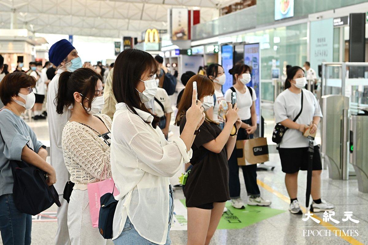 People watch friends and family depart at the Hong Kong airport. (Terence Tang/The Epoch Times)