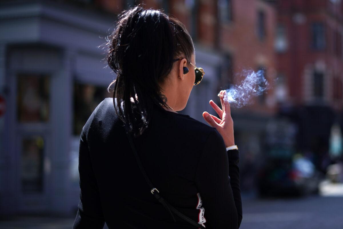 A woman smokes a cigarette in the spring sunshine as pandemic lockdown restrictions ease in Manchester's Northern Quarter in the United Kingdom on April 23, 2021. (Christopher Furlong/Getty Images)