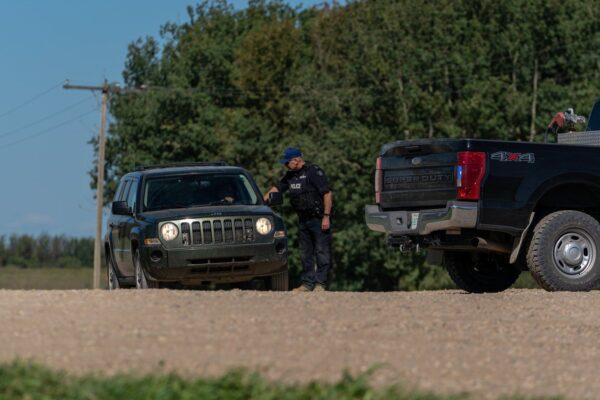 An RCMP officer interacts with a driver at a police roadblock in James Smith Cree Nation, Sask., on Sept. 6, 2022. (The Canadian Press/Heywood Yu)