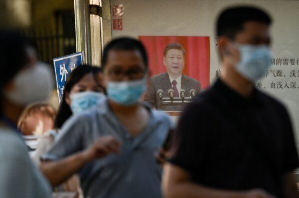 People line up to be tested for the COVID-19 coronavirus next to a propaganda poster showing China's President Xi Jinping on a bulletin board in Beijing on Aug. 31, 2022. (JADE GAO/AFP via Getty Images)