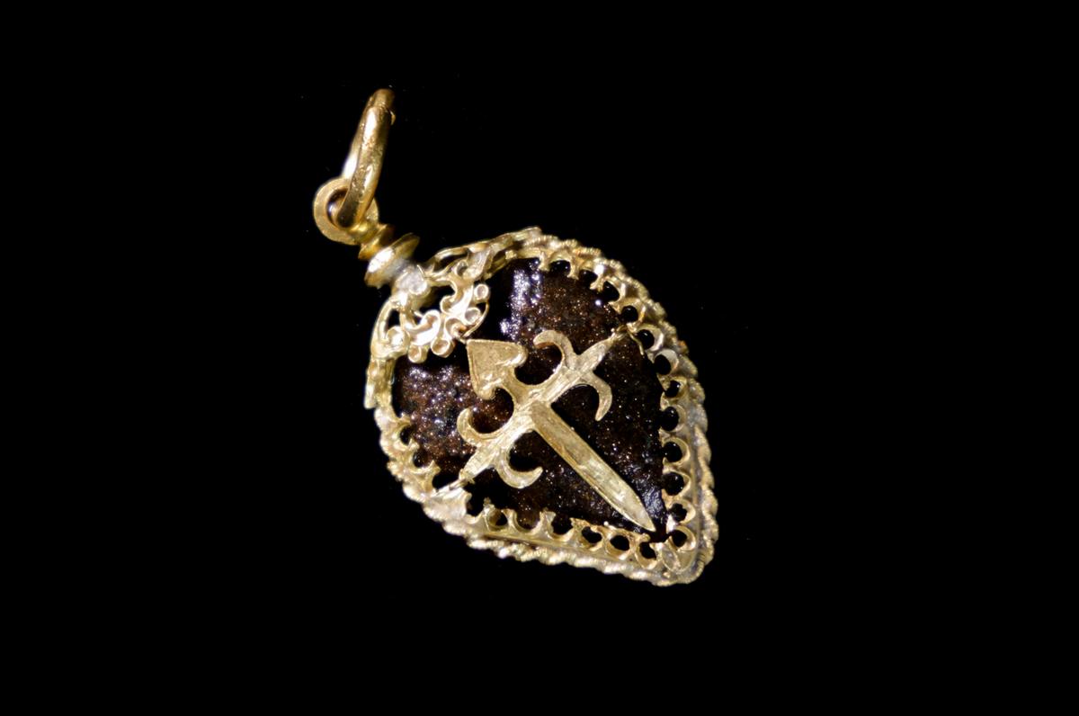 Gold and bezoar stone scallop-shaped pendant of the Order of Santiago with a cross of St. James at center. (Courtesy of Nathaniel Harrington/Allen Exploration via <a href="https://www.bahamasmaritimemuseum.com/">Bahamas Maritime Museum</a>).