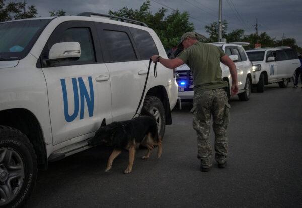 Ukrainian serviceman with a dog checks a motorcade transporting a part of the International Atomic Energy Agency (IAEA) mission coming back from a Zaporizhzhia nuclear power plant at a Ukrainian checkpoint in Zaporizhzhia region, Ukraine, on Sept. 1, 2022, amid Russia's invasion of Ukraine. (Anna Voitenko/Reuters)