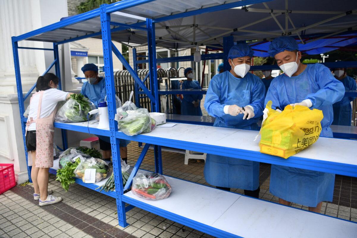 Workers in protective suits prepare to deliver food supplies placed on a rack outside a residential compound to its residents in Chengdu, Sichuan province, China, on Sept. 2, 2022. (cnsphoto via Reuters)