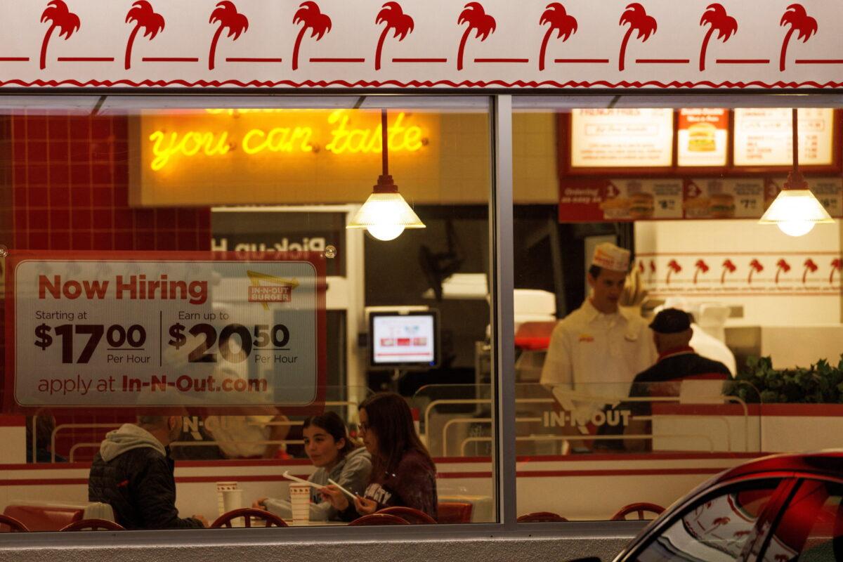 A "Now hiring" sign is displayed on the window of an IN-N-OUT fast-food restaurant in Encinitas, Calif., U.S., May 9, 2022. (Mike Blake/Reuters)