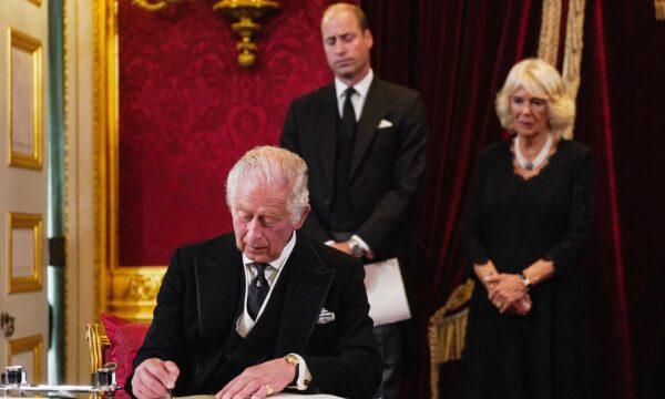Britain's Prince William, Prince of Wales (C), and Camilla, Queen Consort (R) watch as King Charles III signs a document during a meeting of the Accession Council in St James's Palace in London on Sept. 10, 2022. (Victoria Jones/Pppl/AFP via Getty Images)