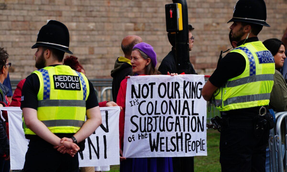Two protesters hold placards ahead of King Charles III's Accession Proclamation Ceremony at Cardiff Castle, Wales, on Sept. 11, 2022. (Ben Birchall/PA Media)