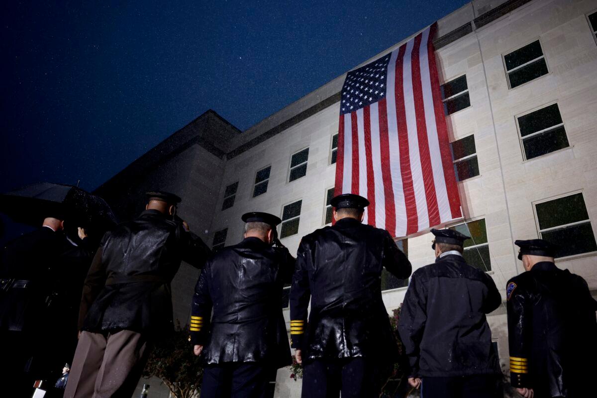 Members of the military and first responders stand in salute as an American flag is unfurled on the side of the Pentagon to commemorate the 21st anniversary of the 9/11 terrorist attacks, in Arlington, Va., on Sept. 11, 2022. (Anna Moneymaker/Getty Images)