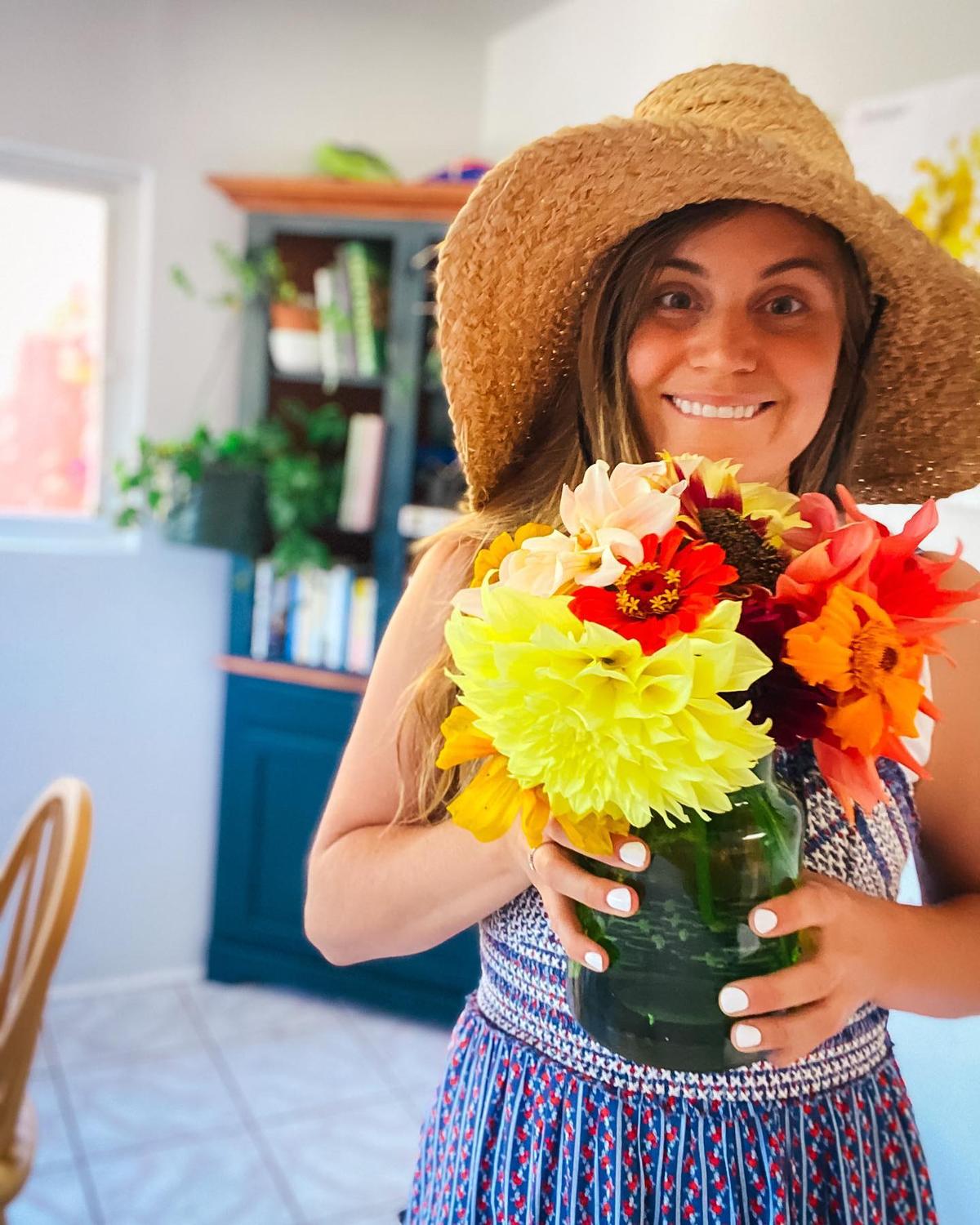 Taylor Raine Koutroumbis with a vase of flowers she grew in her garden. (Courtesy of <a href="https://www.instagram.com/mykidsaredirtyagain/">Taylor Raine</a>)