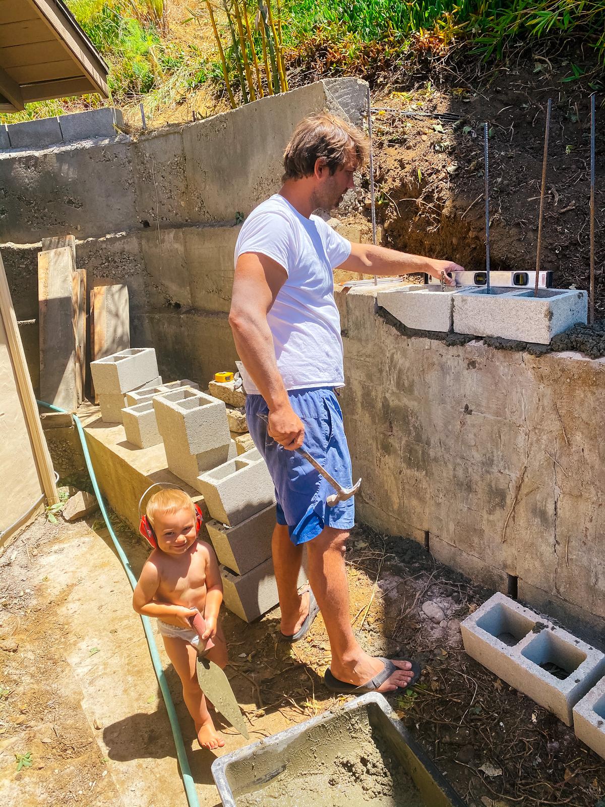 Stelios Koutroumbis works on his backyard wall with the help of his son, Christopher. (Courtesy of <a href="https://www.instagram.com/mykidsaredirtyagain/">Taylor Raine</a>)