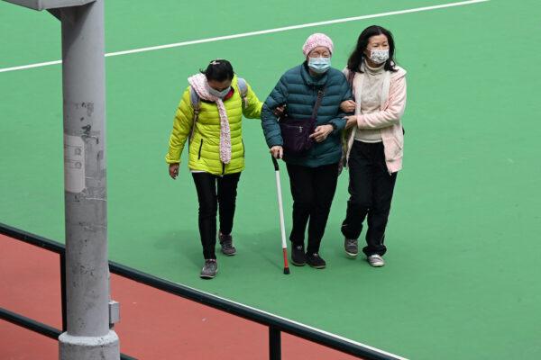 An elderly woman is escorted for COVID-19 testing at a sports ground in Hong Kong on Feb. 23, 2022. (Peter Parks/AFP via Getty Images)