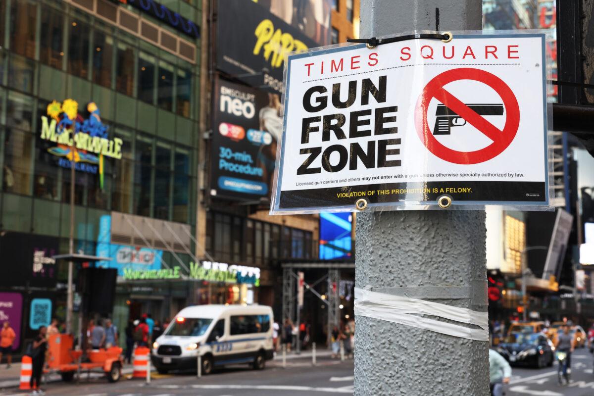 People walk past a "Gun Free Zone" sign posted on 40th Street and 7th Avenue in New York City, on Aug. 31, 2022. (Michael M. Santiago/Getty Images)