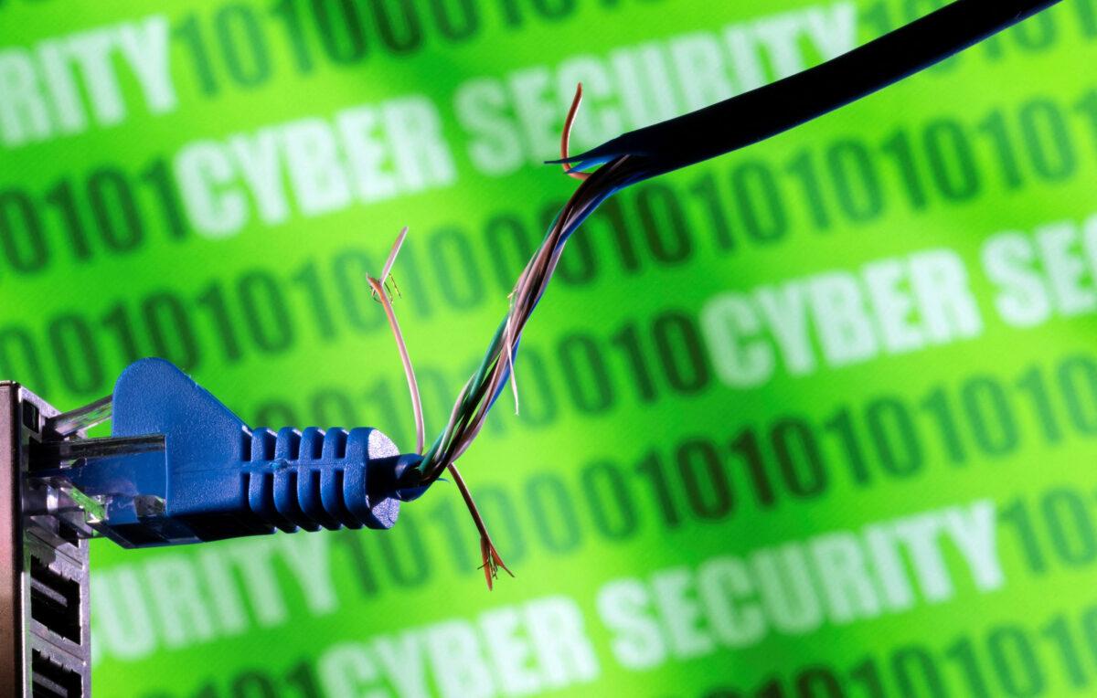 Broken Ethernet cable in front of binary code and words "cyber security" in a photo illustration taken on March 8, 2022. (Dado Ruvic/Illustration/Reuters)