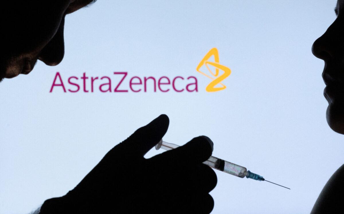 People pose with syringe with needle in front of displayed AstraZeneca logo on Dec. 11, 2021. (Dado Ruvic/Illustration/Reuters)