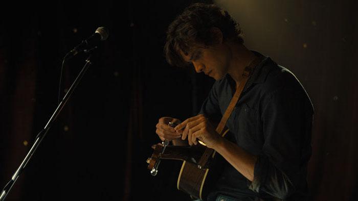 Owen (Douglas Smith) tunes his guitar, in "The Swearing Jar." (Gravitas Ventures)