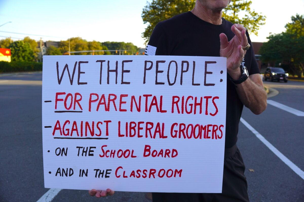 A demonstrator holds a sign favoring parental rights and against liberal gender ideology outside Luther Jackson Middle School in Falls Church, Va., before a Fairfax County Public Schools board meeting on Sept. 15, 2022. (Terri Wu/The Epoch Times)