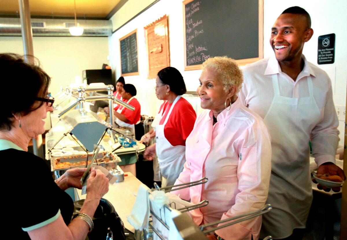 A customer picks up food from Sweetie Pie's owner Robbie Montgomery (2nd R) and Montgomery's son James "Tim" Norman (R) at the shop in St. Louis on April 19, 2011. (David Carson/St. Louis Post-Dispatch via AP)