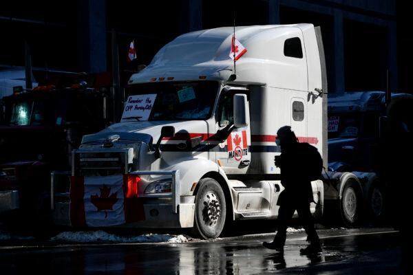 A person crosses the street beside a big rig parked on Metcalfe Street in downtown Ottawa during the second week of the Freedom Convoy protest against COVID-19 mandates and restrictions, on Feb. 7, 2022. (The Canadian Press/Justin Tang)