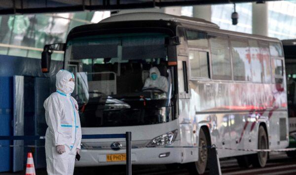A health worker wearing a personal protection suit stands next to a bus used to transport people to COVID-19 quarantine in China, in a file photo. (Nicolas Asfouri/AFP via Getty Images)