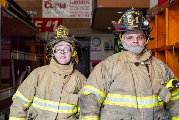 Briana and David Moore (R) dress themselves up in firefighter gear at Neversink Engine Company in Port Jervis, N.Y., on Sept. 9, 2022. (Cara Ding/The Epoch Times)