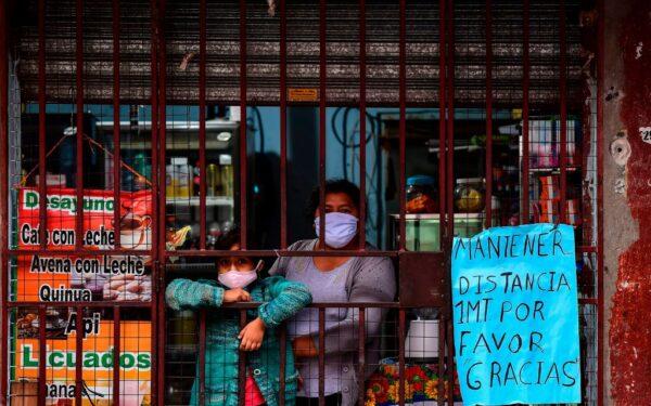 A woman and her daughter, both wearing face masks, look out at the street from of a shop in downtown Buenos Aires, Argentina, on May 5, 2020. (Ronaldo Schemidt/AFP via Getty Images)